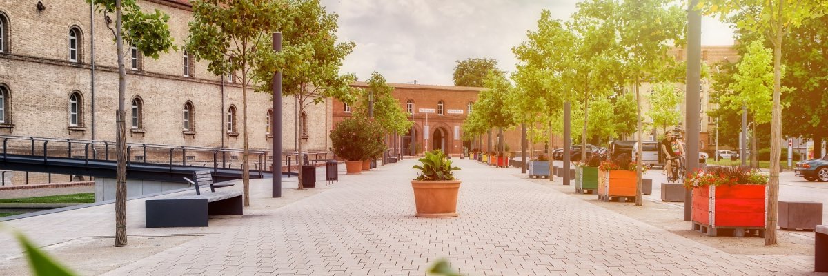 Blick auf den Fußweg vom Paradeplatz, gesäumt mit Sitzbänken und bunt bepflanzten Holzbeeten