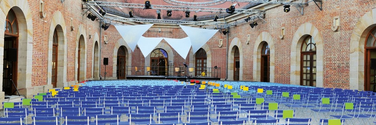 Innenhof des Hufeisens mit blauen Stühlen und Bühne