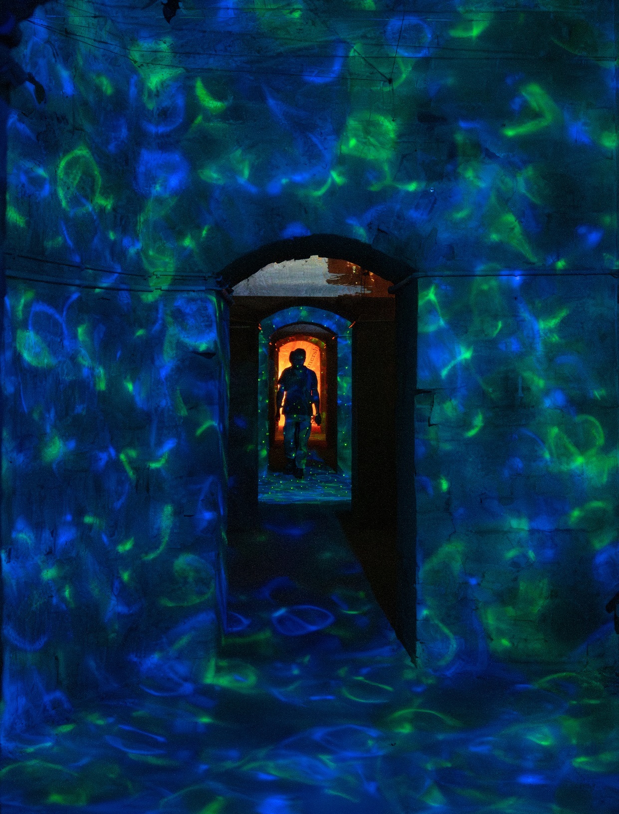 Foto aus den Festungsgängen die durch Lichttechnik in eine Unterwasserwelt verwandelt wurden. Viele blaue & grüne Farbe spiegeln sich an den Wänden