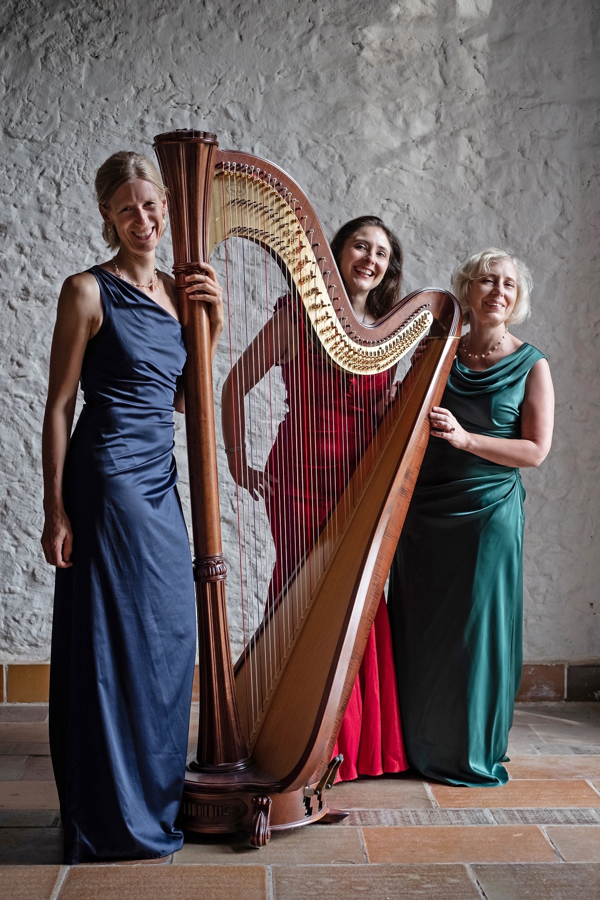 Die drei Musikerinnen in bunten Kleider mit einer großen Harfe in der Mitte.