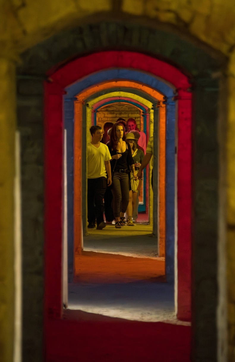 Foto aus den bunt beleuchteten Minengängen der Festung; die WALK-Teilnehmenden laufen in Gruppen durch die Gänge zu den einzelnen Stationen