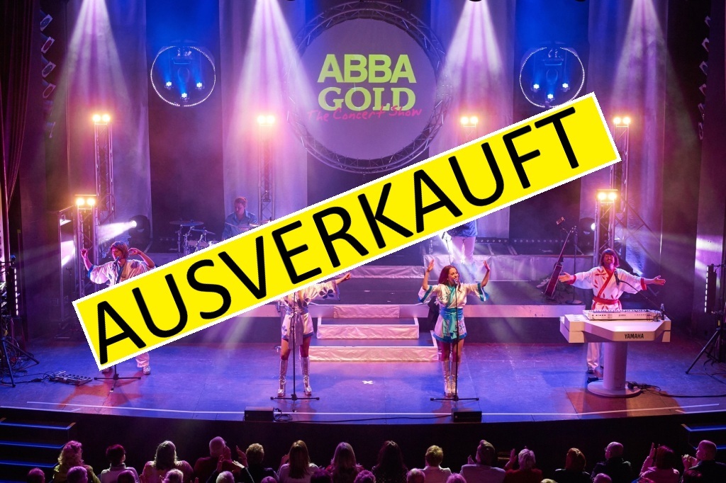 Szenenbild aus der Show - Am vorderen Bühnenrand stehen die Sängerinnen und Sänger in Abba-Kostümen, im Hintergund sind weitere Musiker mit Instrumenten zu sehen.