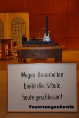 Schild mit Text "Wegen Bauarbeitern bleibt die Schule heute geschlossen / Feuerzangenbowle"