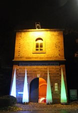 Beleuchtetes Eingangsportal Fronte Beckers mit vier farbig leuchtenden Lichtkegeln